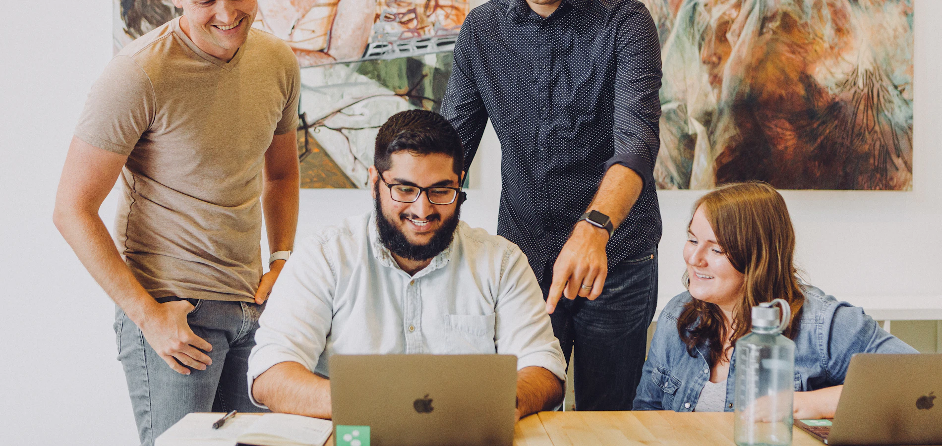 Colleagues gathered around a laptop, smiling during a training session
