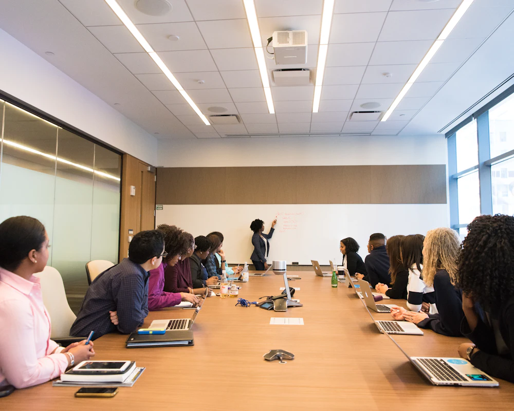 A presenter leading a session with colleagues around a boardroom table