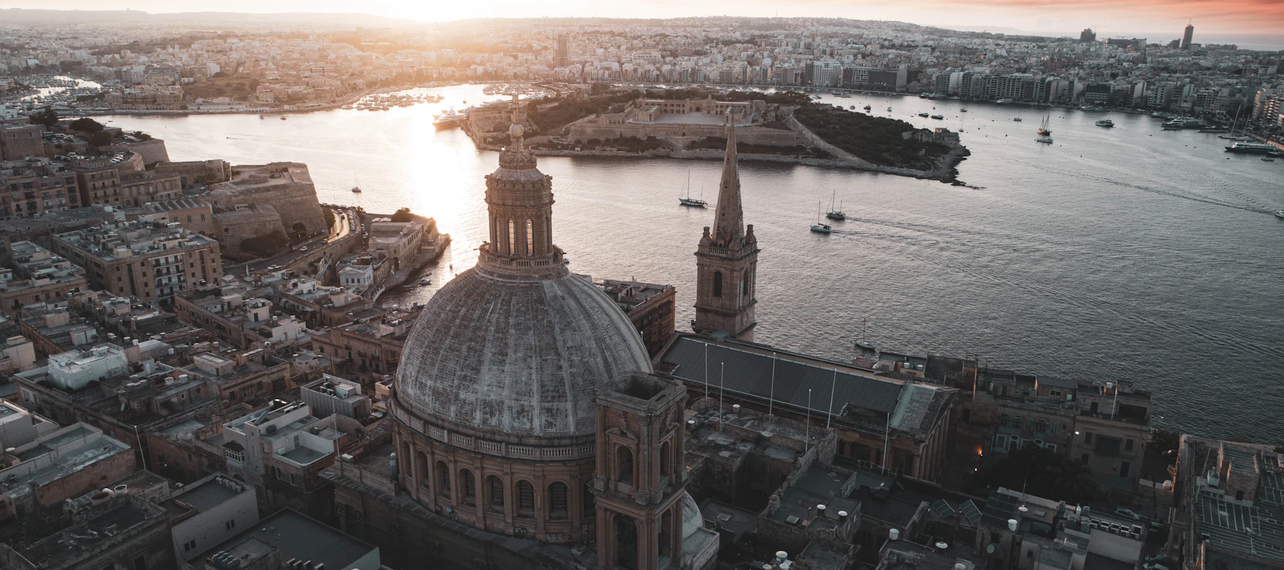 The domes and spires of Valletta, Malta, above the harbour at sunset