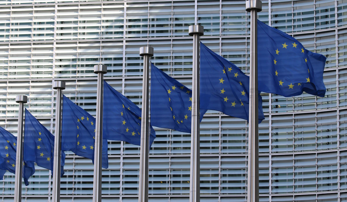 A row of European Union flags outside a modern office building