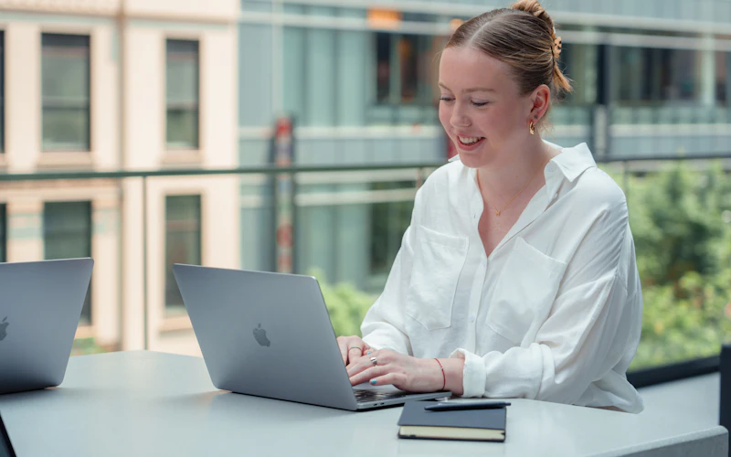 A professional working through an online course on her laptop by a bright window