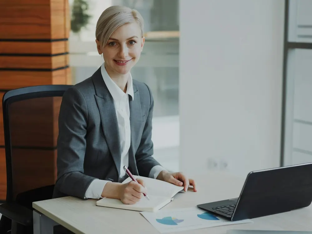 A smiling professional making notes at her desk
