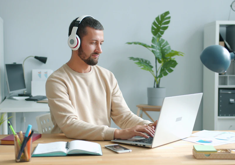 A professional with headphones following an online course at his desk