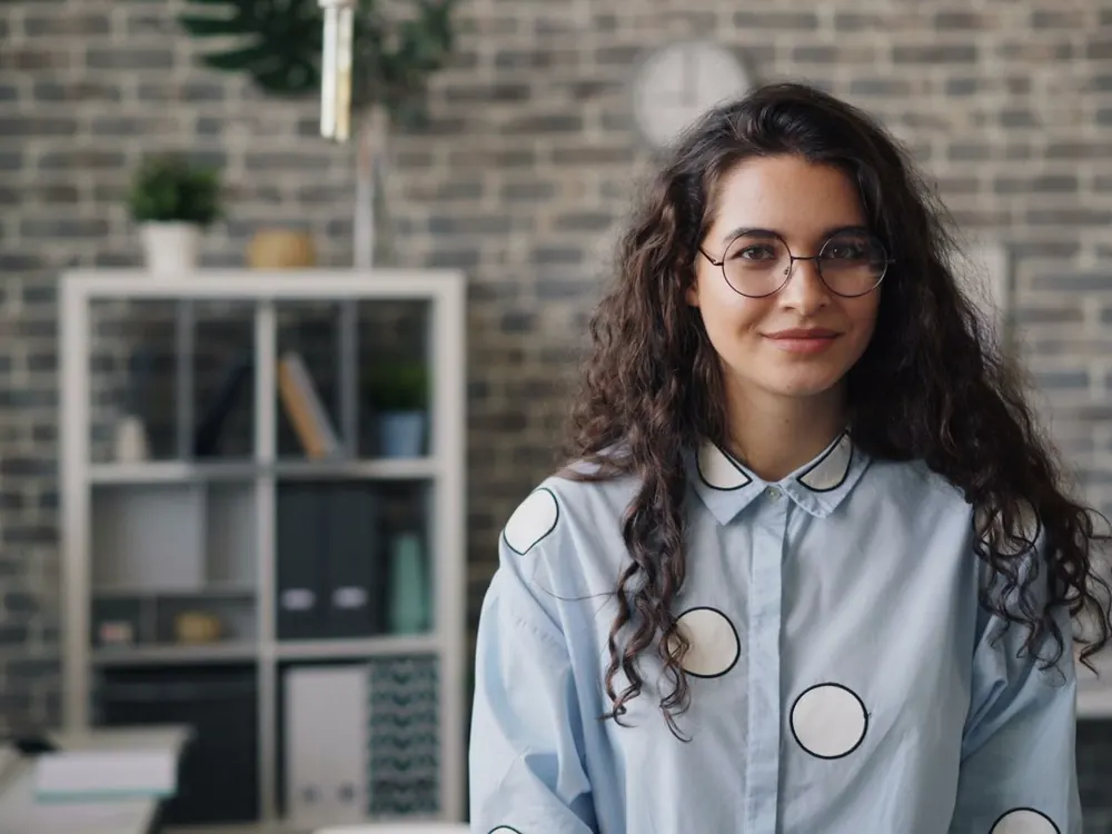 A smiling professional in a bright office, ready to help with your question